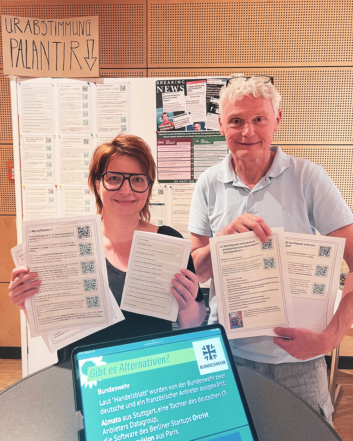 Jana Akyildiz (OV Rielasingen-Worblingen) und Peter Alexander (OV Raum Stockach) beim Infostand zur Palantir-Urabstimmung mit den Info-Postern in der Hand und dahinter an der Stellwand